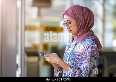 Junge muslimische Frau mit Handy im Freien Stockfoto