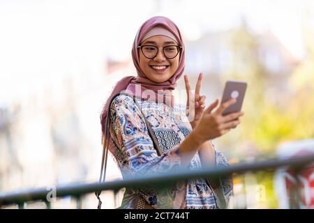 Portrait einer glücklichen muslimischen Frau, die ein Selfie mit macht Ihr Mobiltelefon Stockfoto