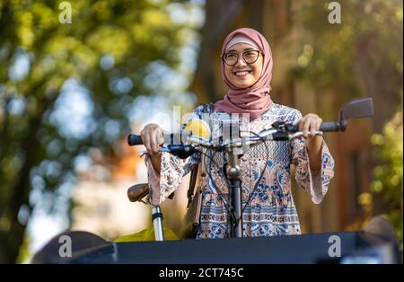 Selbstbewusste muslimische Frau mit Lastenrad im städtischen Bereich Stockfoto