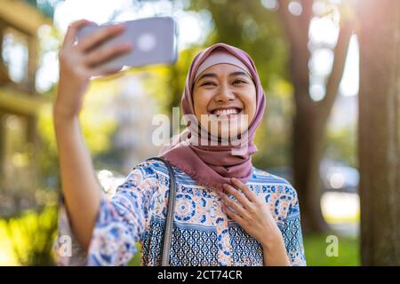 Portrait einer glücklichen muslimischen Frau, die ein Selfie mit macht Ihr Mobiltelefon Stockfoto