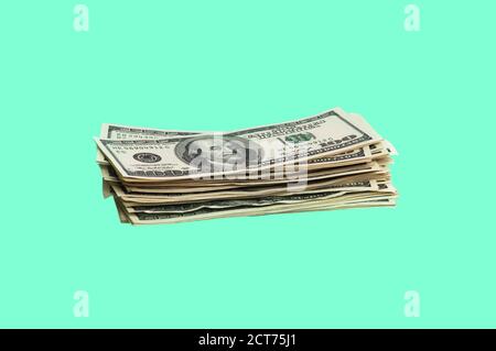 Isoliertes Dollarpaket. Ein großer Stapel von hundert-Dollar-Scheinen liegt auf einem grünen Hintergrund in der Mitte des Bildes. Nahaufnahme. Kontrastreiche Farben Stockfoto