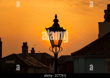 Straßenlampe im Vintage-Stil mit goldenem Sonnenaufgang und Dächern im Hintergrund. Aldeburgh, Suffolk. VEREINIGTES KÖNIGREICH Stockfoto