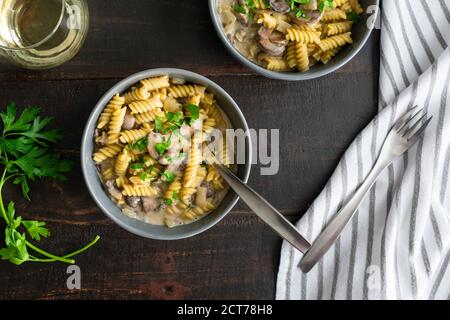 Veganer Pilz Stroganoff: Schüsseln mit Rotini-Pasta und Cremini-Pilzen in einer cremigen Weißweinsauce Stockfoto