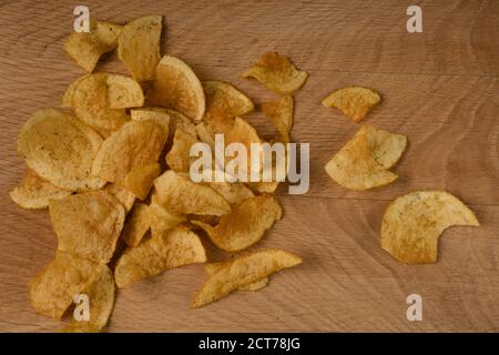 Appetitliche Kartoffelchips sind auf einem Holzbrett verstreut Stockfoto