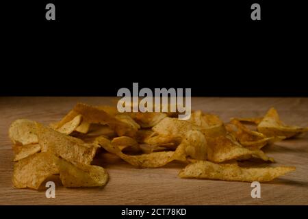 Appetitliche Kartoffelchips sind auf einem Holzbrett verstreut Stockfoto