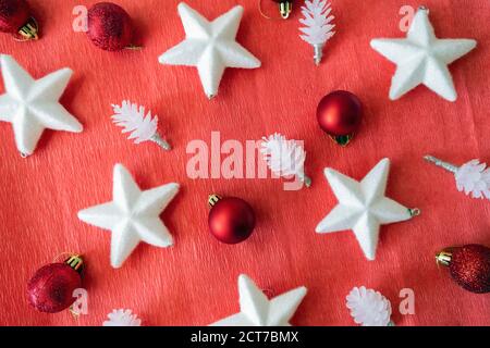 Weihnachtliche Gestaltung. Blick von oben auf Weihnachtsschmuck. Vor rotem Hintergrund. Sterne, Unebenheiten und Bälle. Stockfoto