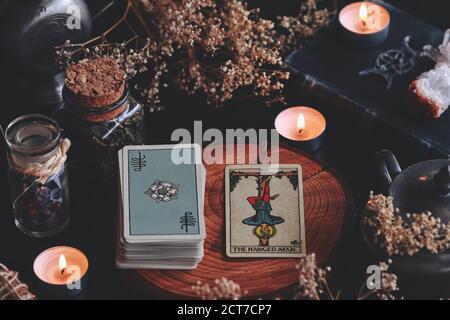 Die gehängte man Rider Waite Smith Mini Tarot Karte auf Holz Natur Display mit getrockneten Blumen und Kräutern. In einem Zentrum für Meditationszwecke dargestellt Stockfoto