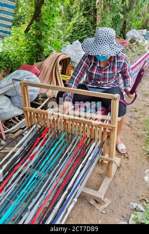 Frau, die am Webstuhl arbeitet und einen ausgestreckten Teppich (18 Meter) webt, der in kleinere Längen unterteilt werden soll, Bien Tien, Vietnam. Stockfoto