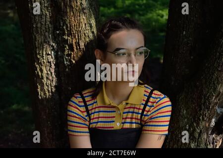 Junge Person, die an einem Baum sitzt Stockfoto