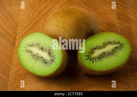 Kiwi eine ganze und zwei Hälften liegen auf einem hölzernen Platine Stockfoto