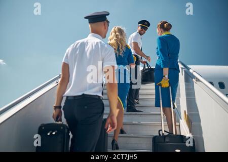 Kruppe von Menschen, die mit zum Passagierflugzeug hochheben Rollsäcke in den Händen Stockfoto