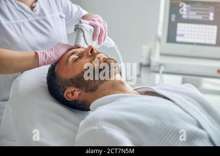 Arzt Kosmetikerin Behandlung der männlichen Haut mit Laser-Gerät Stockfoto