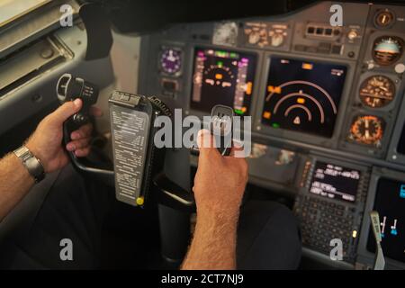 Professioneller männlicher Pilot, der im Passagierflugzeug navigiert Stockfoto