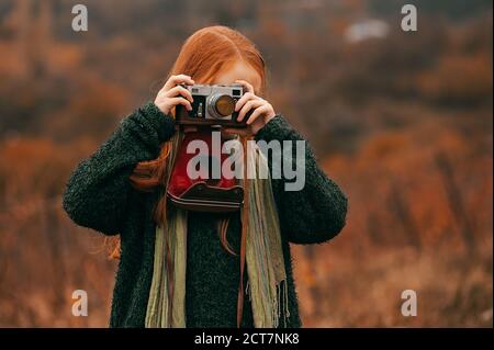 Mädchen mit roten Haaren macht ein Bild mit einem Vintage Kamera Stockfoto