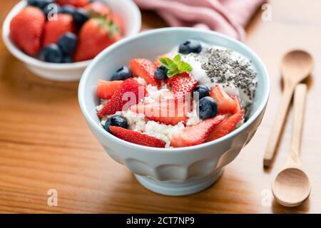 Quark, Quark mit frischen Sommerbeeren in einer Schüssel auf Holztisch. Gesundes Frühstück oder Snacks Stockfoto