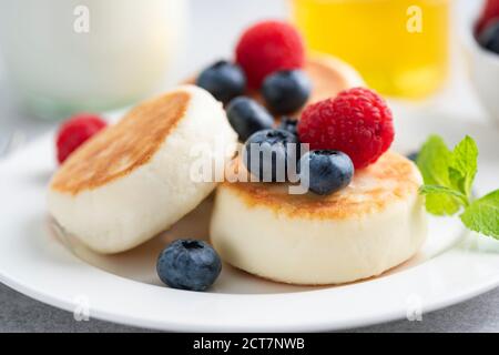 Syrniki, Hüttenkäse fritters mit Beeren auf dem Teller, Nahaufnahme. Frühstück oder Dessert Stockfoto