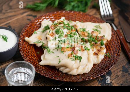 Pierogi oder Vareniki, mit Kartoffeln gefüllte Knödel, serviert mit gebratener Zwiebel, Dill und saurer Sahne Stockfoto