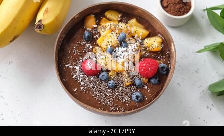 Schokoladen-Smoothie-Schale mit Superfood-Toppings Chia-Samen, Mango, Heidelbeere, Himbeeren und Kokosnuss Stockfoto