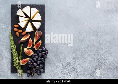 Camembert Käse mit Feigen und Trauben auf Schiefer. Draufsicht, Kopierbereich. Französische Käseplatte für Feinschmecker Stockfoto