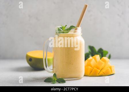 Köstlicher Mango Smoothie im Glas auf grauem Hintergrund mit Kopierraum. Erfrischender Sommerdrink Stockfoto