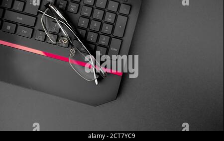 Nahaufnahme der schwarzen Tastatur mit Brille auf dem Tisch. Büro, Arbeiten von zu Hause Konzept Stockfoto