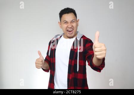 Porträt des jungen asiatischen Mann zeigt Daumen nach oben Zeichen, glücklich lächelnde Person, OK Deal Konzept Stockfoto