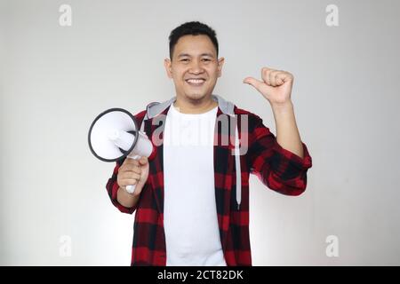 Junger asiatischer Mann, der Ankündigung macht, Marketing-Werbekonzept, lächelnder Ausdruck mit Megaphon, auf weißem Hintergrund Stockfoto
