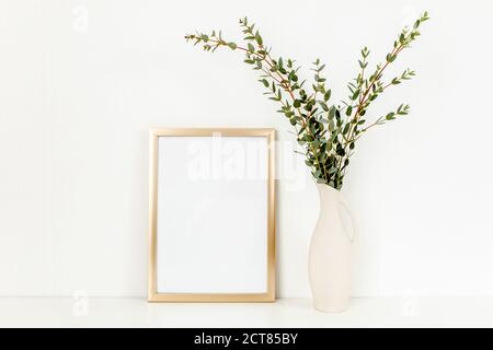 Blanker Rahmen Mockup mit einem Zweige von Eukalyptus in Vase auf Tisch auf hellem Hintergrund. Inneneinrichtung. Blog, Website oder Social Media Konzept. Stockfoto