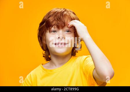 Ein verträumter rothaariger Junge berührt sein Gesicht mit der Hand Stockfoto