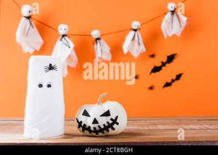 Lustige Halloween Tag Dekoration Party, White Geist gruseliges Gesicht und Glas Wasser mit Verband und Kürbis auf Holztisch gewickelt, Studio Schuss isoliert o Stockfoto