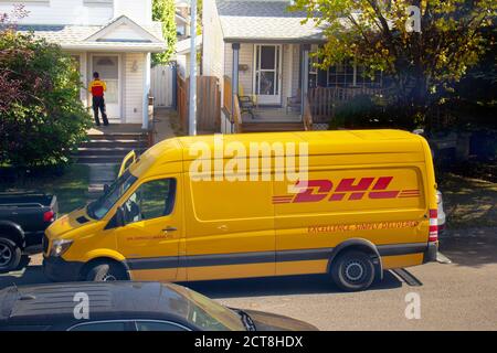 Calgary, Alberta, Kanada. September 21 2020. Ein DHL-Mitarbeiter, der ein Paket vor der Haustür eines Hauses ausliefert. Stockfoto