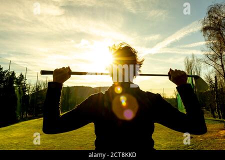 Golfer Leaning ihren Golfclub auf ihren Schultern mit Sonnenlicht. Stockfoto