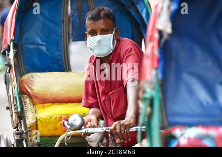 Peking, China. September 2020. Ein Rikscha-Abzieher mit Gesichtsmaske ist am 21. September 2020 auf einer Straße in Dhaka, Bangladesch, zu sehen. Quelle: Xinhua/Alamy Live News Stockfoto