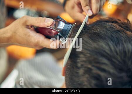 Qualifizierte Friseur mit elektrischen Haarschneider für eine Frisur von Der Kunde Stockfoto