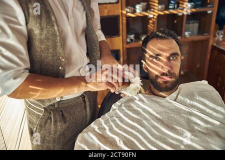 Bärtiger junger Mann, der sich im Friseurladen frisch rasieren kann Stockfoto