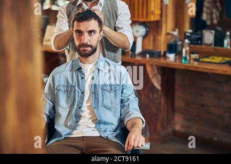 Brunette Mann suchen ernst während Haar Styling Stockfoto