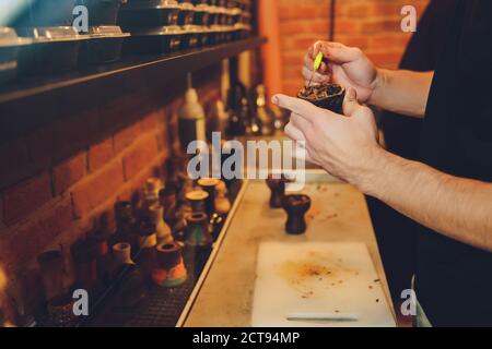 Eine Person nimmt Tabak. Die Person bereitet eine Shisha vor. Es gibt einen Tisch. Stockfoto