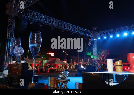Portrait einer nächtlichen Veranstaltung oder Zeremonie mit leerer Tanzfläche und Weinglas im Rahmen, Zeltaufbau im Hintergrund, Outdoor-Nachtaufnahme, Hochzeit Stockfoto