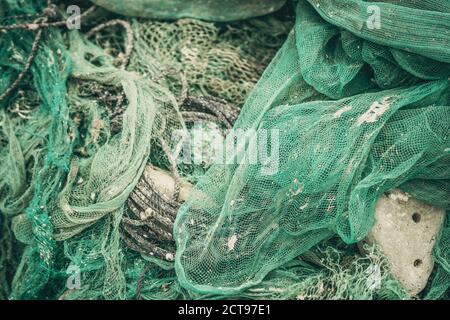 Nahaufnahme Stapel von grünem Nylon Multi bunte helle Fischnetze mit Stücken von weißen Korallen und alten Seilen in Fischerdorf. Stillleben Hintergrund Stockfoto