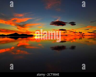 Dramatischer Himmel. Orangefarbener Sonnenuntergang. Beeindruckender Sonnenuntergang. Wunderschöne Wüstennatur. Farbiger Himmel. Erstaunliche Wolke Reflexion im Wasser. Salar de Uyuni Stockfoto