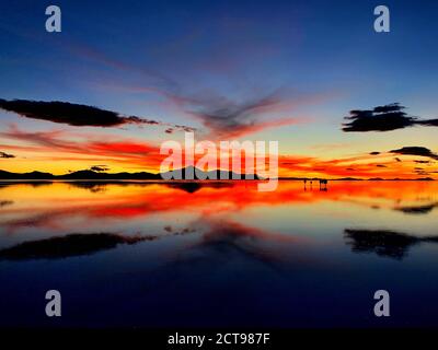 Dramatischer Sonnenuntergang Himmel über Salzsee, Salar de Uyuni, Bolivien. Atemberaubende Landschaft der Wüste Atacama. Flammender roter surrealer Sonnenuntergang über Salzflächen Uyuni. Stockfoto