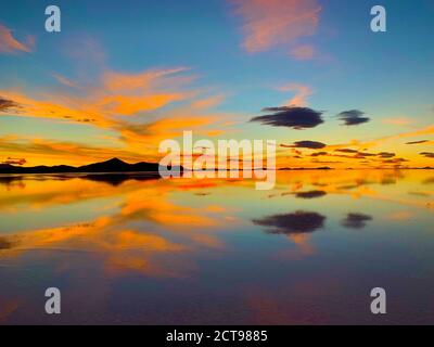 Atemberaubender orangefarbener Sonnenuntergang. Heller Sonnenuntergang Himmel. Erstaunliche Reflexion der himmlischen Wolken im Seewasser. Uyuni Salt Flats, Bolivien. Surreale Landschaft. Stockfoto