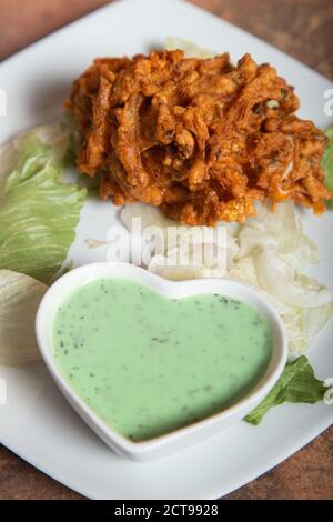 Nahaufnahme der indischen Zwiebel bhaji Vorspeise mit pakistanischen Joghurt grüne Sauce.isolierte Bild. Stockfoto