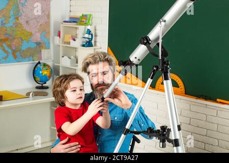 Vater lehrt Sohn. Kinder mit Teleskop. Kinder lernen. Kinder aus der Grundschule. Stockfoto