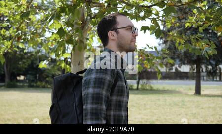 Ein hübscher junger Mann in Brille und mit Rucksack zu Fuß Entlang Stockfoto
