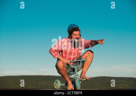 Lustiger Mann auf einem Fahrrad. Emotionaler verrückter Kerl auf einem Kinderfahrrad. Stockfoto