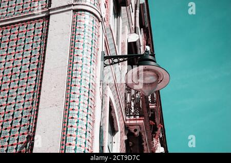 Ecke eines typischen alten Gebäudes im Zentrum von Lissabon (Portugal). Bunte Keramikfliesen (Azulejos) mit geometrischem Muster und einer hängenden Laterne. T Stockfoto