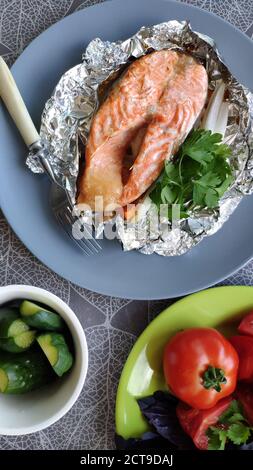 Draufsicht auf foliengebackene Lachssteaks und frisches Gemüse, selektiver Fokus Stockfoto