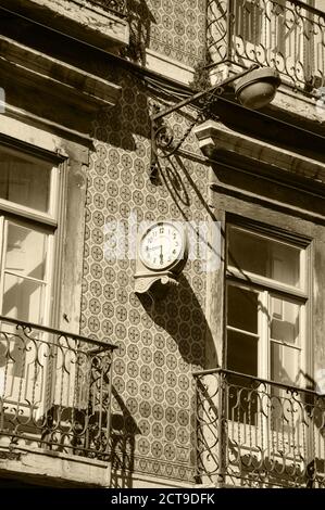 Uhr und Laterne auf dem typischen alten Gebäude mit Keramikfliesen (Azulejos) im Zentrum von Lissabon (Portugal) dekoriert. Sepia historisches Foto. Stockfoto