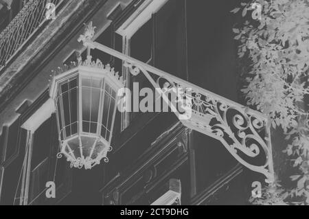 Laterne mit Lissabon-Symbol (Schiff mit zwei Raben) auf dem alten Gebäude im Zentrum von Lissabon (Portugal). Gealtertes Foto. Schwarz und Weiß. Invertierte Farben Stockfoto